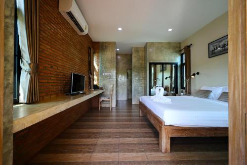 a bedroom with a large white bed and a tv at Chiang Mai Garden Bungalows in Chiang Mai