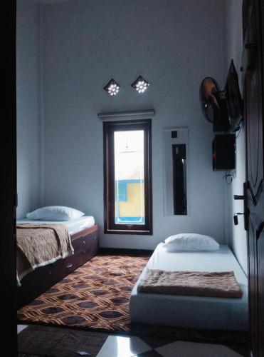two beds in a room with a window at AN homestay2 Syariah in Wonosobo