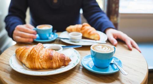 a person sitting at a table with cups of coffee and croissants at Le Due Muse b&b in Pagani