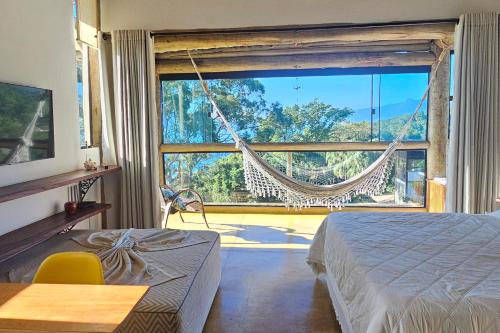a bedroom with a hammock in front of a large window at OPN Guest House Ilhabela in Ilhabela