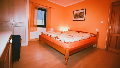 a bedroom with a bed in an orange room at Chata Kačerov in Kašperské Hory