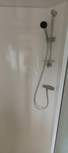 a shower with a shower head on a wall at frankys presthaven retreat in Talacre
