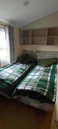 a bedroom with a bed with a green and white blanket at frankys presthaven retreat in Talacre