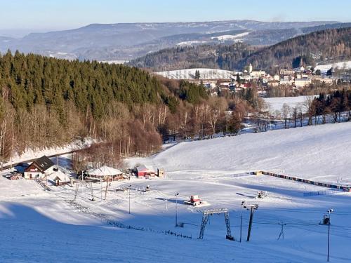 a ski slope with snow and a town in the background at Hostinec Lovecký zámeček in Olešnice v Orlických horách