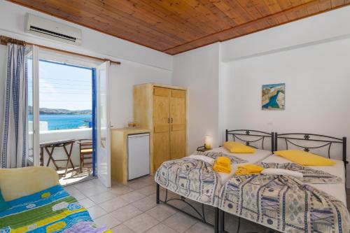 a bedroom with two beds and a balcony at Apollon Rooms in Pollonia