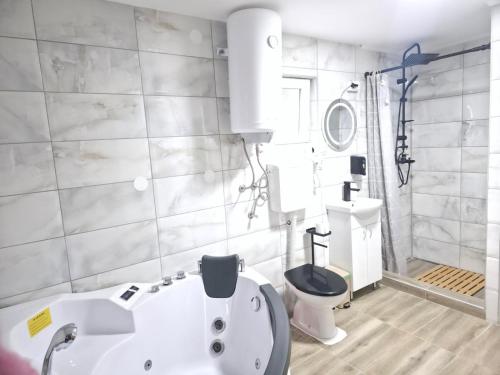 a bathroom with a white tub and a toilet at Black House Spa in Gamzigrad