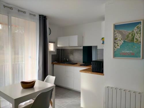 グレウー・レ・バンにあるStudio Le Provence 2 étoiles tout équipé, wifi, parkingのキッチン(白いキャビネット、テーブル、テーブル、椅子付)