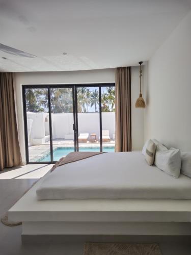 a bedroom with a large bed with a view of a pool at Amour Beach Villas in Paje