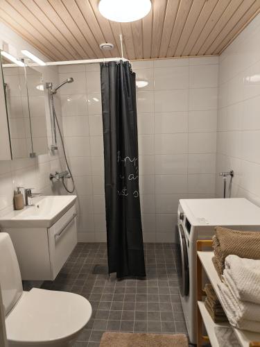 a bathroom with a black shower curtain and a sink at Tievastreet Harmony Apartment in Rovaniemi