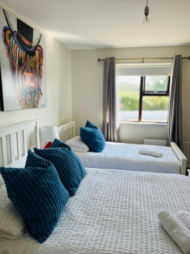 two beds with blue pillows in a bedroom at The Chroma Cottage in Cock Hill