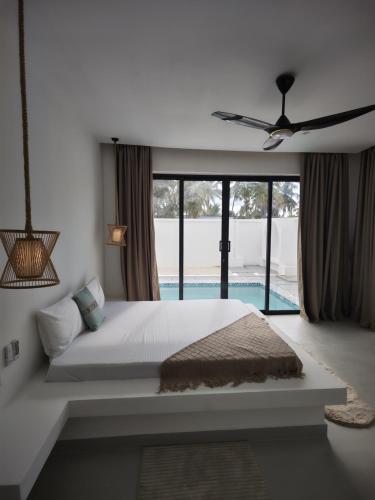 een slaapkamer met een groot bed en een groot raam bij Amour Beach Villas in Paje