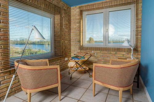 a room with two chairs and two windows at Stylish Apartment Zander On The Eider River Bend in Süderstapel