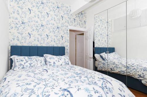 a bedroom with a blue and white bed and a mirror at Gorgeous First Floor apartment near Station in London