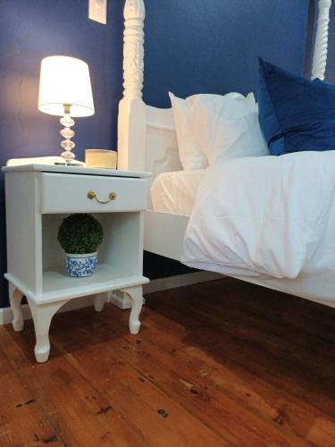 a bed with a nightstand with a lamp and a plant on it at 2 Seconds Avenue in Hilton