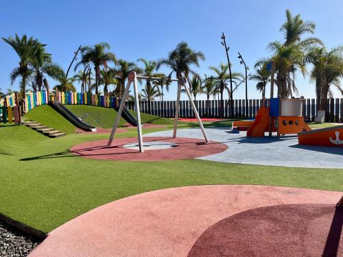 een park met een speeltuin met een glijbaan en schommels bij Castillo Dream en San Bartolome de Tirajana in Castillo del Romeral