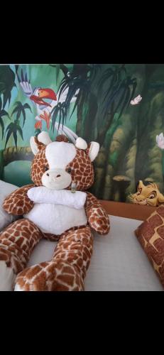 a stuffed giraffe laying on top of a bed at Jungle Duplex with pool 5 min Disneyland in Serris