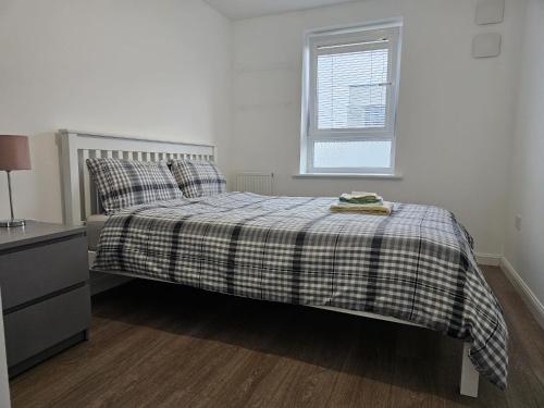 a bedroom with a bed with a plaid blanket and a window at Stylish 2-Bed Flat with Open-Plan Living plus Parking in Edinburgh