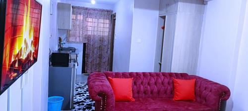 un sofá púrpura en una sala de estar con almohadas rojas en Kwa Engineer, en Wajir
