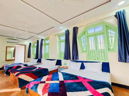 three beds in a room with windows at Johari Heritage Home in Ujjain