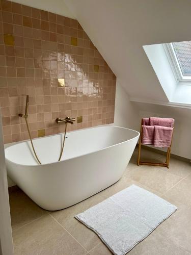 a large white bath tub in a attic bathroom at Les Chantereines maison calme au cœur du vignoble champenois in Brugny-Vaudancourt