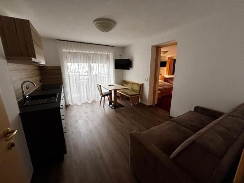 a kitchen and a living room with a couch and a table at Hotel Laerchenhain in San Valentino alla Muta