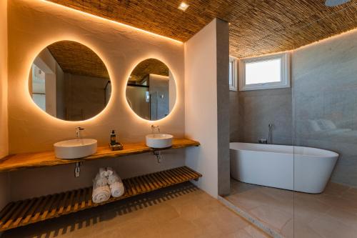 a bathroom with two sinks and a tub and a mirror at Pousada Aysú in Japaratinga