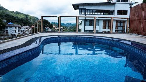 a swimming pool with blue water in front of a house at Manthra Leisure in Kandy