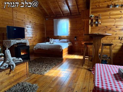 a bedroom with a bed and a fireplace in a log cabin at בלב הגורן belevhagoren in Goren