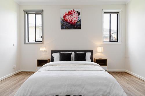 Modern 4BR Home Spacious & Family Friendly في Melton South: غرفة نوم بيضاء بسرير كبير ونوافذ