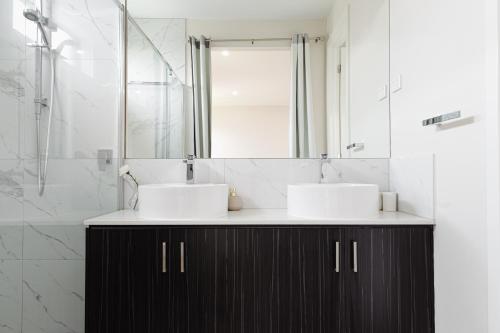 Modern 4BR Home Spacious & Family Friendly في Melton South: حمام به مغسلتين ومرآة