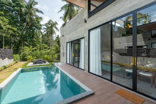 een zwembad in de achtertuin van een huis met glazen wanden bij Balance Village in Ko Phangan
