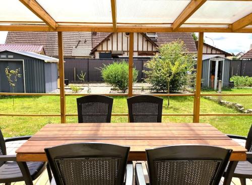 a wooden table and chairs in a backyard at La petite cauchoise in Bacqueville-en-Caux
