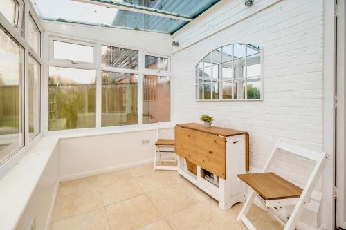 een afgeschermde veranda met een bureau en een stoel bij Seaside Luxury Cottage Aldeburgh in Aldeburgh