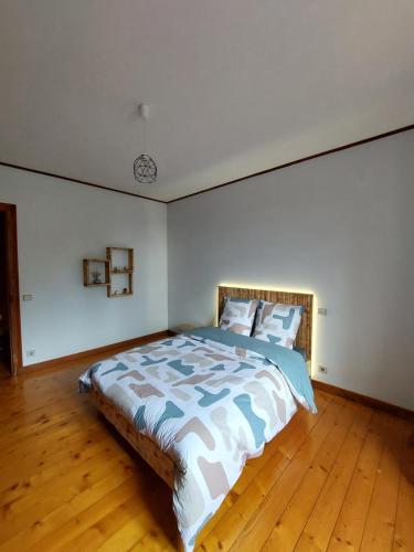 a bedroom with a large bed with a wooden floor at Gîte "EN VALROMEY" au pied du Grand Colombier in Munet