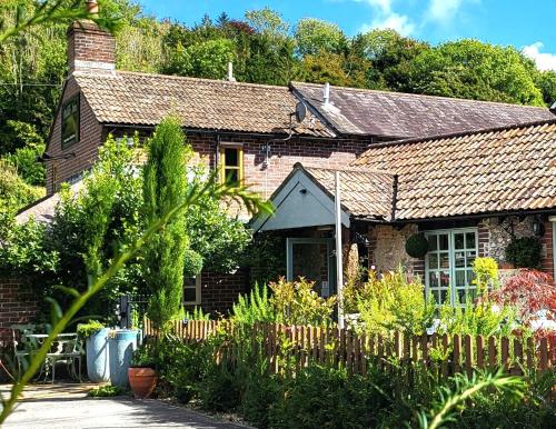 a brick house with a garden in front of it at Escape the Ordinary in Piddletrenthide