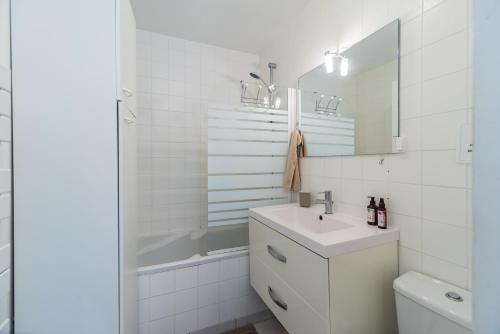 ein weißes Badezimmer mit Waschbecken und Spiegel in der Unterkunft Le Refuge de la Clarté, draps et serviettes inclus in Perros-Guirec