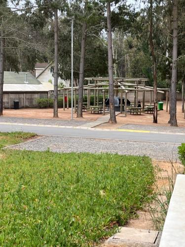 Cómodo Depto en bosques de la candelaria في ألغاروبو: حديقة بها مقاعد وأشجار وطريق