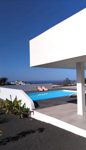 a swimming pool next to a white building with a blue sky at Casa Calma in Las Breñas