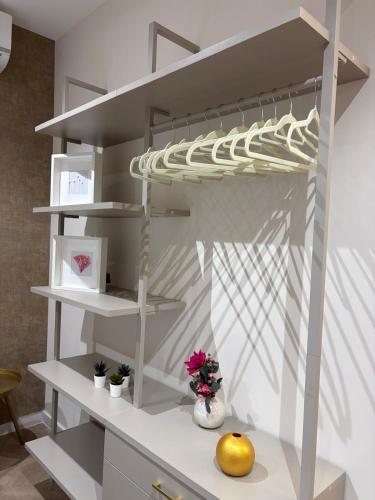 Un estante blanco en una habitación con algunas flores sobre una mesa. en 50 Passi dal Duomo, en Marcianise