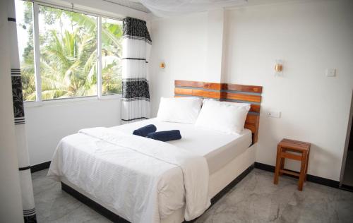a bedroom with a bed with white sheets and a window at Rokky Hill Cottage Ella in Ella