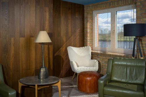a living room with a chair and a table and a lamp at Stylish Apartment Zander On The Eider River Bend in Süderstapel