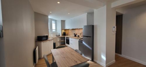a kitchen with a wooden table and a refrigerator at T2 Hyper-centre Brest CHU Morvan & Transports in Brest