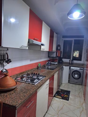 a kitchen with red and white cabinets and a stove at Haytam in Sale