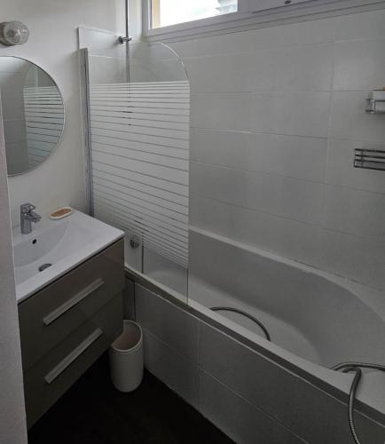 ein Badezimmer mit Badewanne, Waschbecken und Spiegel in der Unterkunft Le petit savoyard in Albertville