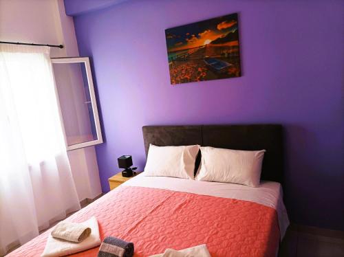 een slaapkamer met een bed met een paarse muur bij OINO APARTMENT in Corfu-stad