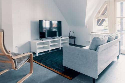 Una sala de estar con un sofá blanco y un televisor. en Moderne 2 Zimmer Wohnung im Herzen von Karlsruhe 64m2 2 OG, en Karlsruhe