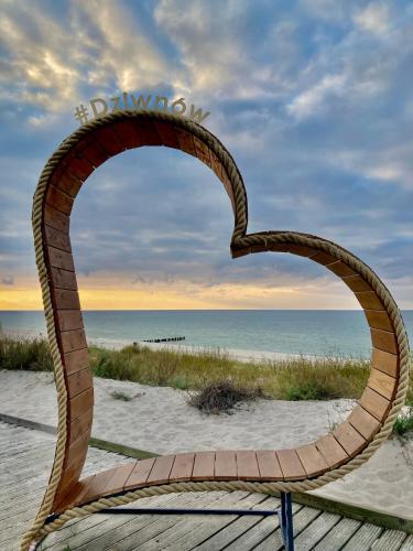 a wooden arch in the sand at the beach at ParaSOL - Baltic Relax - Pool, Jacuzzi, Sauna in Dziwnów