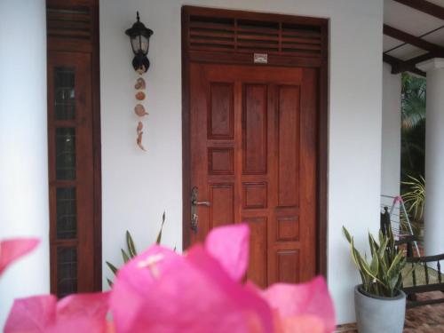 a wooden door with pink flowers in front of it at Bell 412 in Weligama