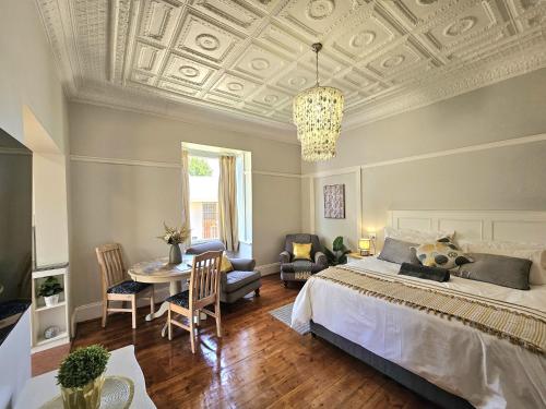 Stylish Cozy Stay at Ferndale House Apartments في بورت ألفريد: غرفة نوم بها سرير وطاولة وكراسي