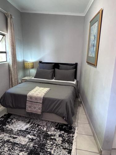 a bedroom with a large bed with a rug at Cozy pool side cottage in Roodepoort